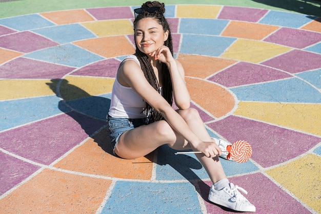 Ragazza con scatola di treccia acconciatura seduto al sole