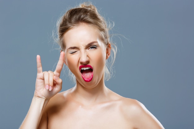 Free photo girl with bright makeup showing rock hand gesture