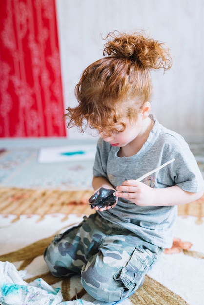 Girl with brush painting palm and sitting on floor