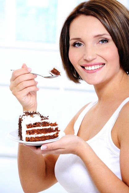 girl with cake on plate brings  spoon to a mouth