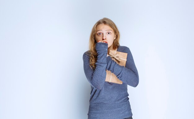 Girl with a cardboard gift box looks terrified and thrilled. 