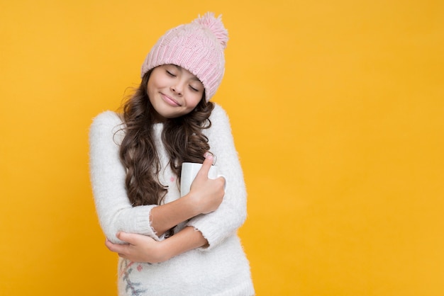 Girl with closed eyes hugging a cup of hot chocolate