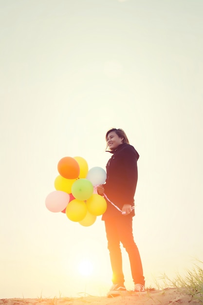 Девушка с воздушными шарами в Coloful заката