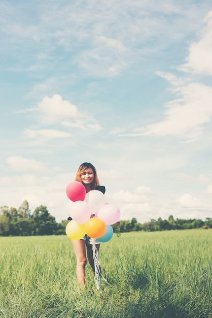 Girl with colored balloons in a field