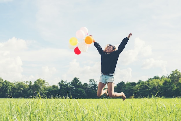 Girl with colored balloons jumping