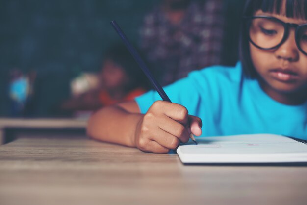  girl with crayon drawing at lesson in the classroom 