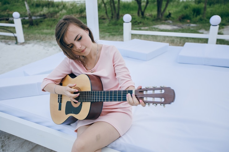Free Photo girl with crooked head while playing a guitar