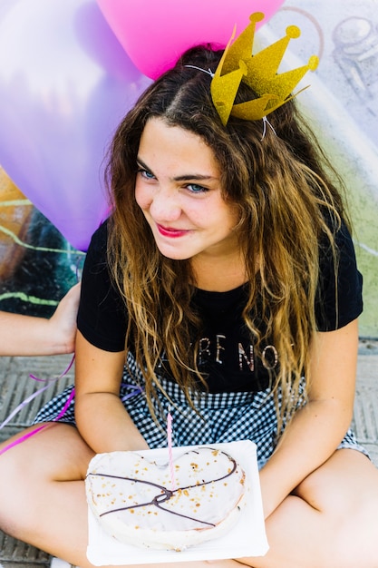 Girl with crown holding birthday pastry