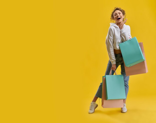 Girl with curly hair standing smiling holding packages