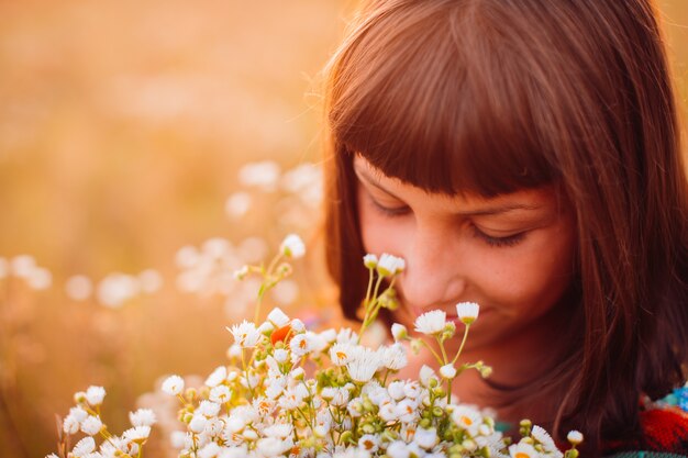 Girl with daisies stands on the field 