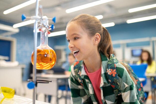 Girl with delight looking at flask in chemistry class