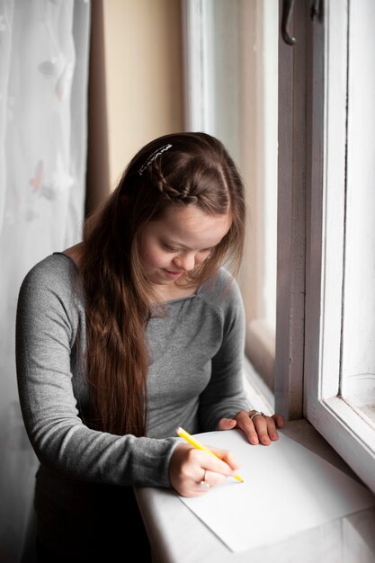 Girl with down syndrome drawing by the window