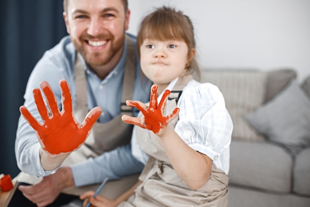 ダウン症の少女と彼女の父親は赤い色で手を描いた