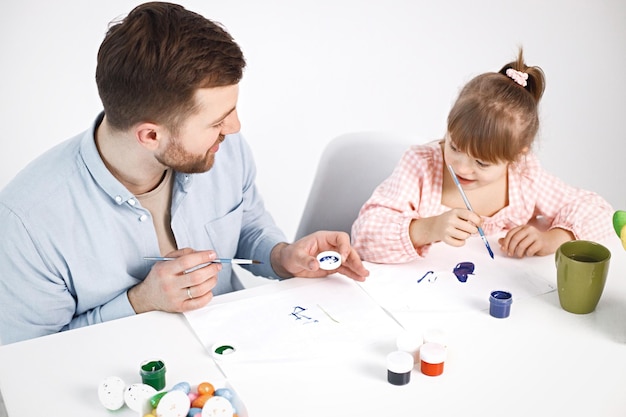 Girl with Down syndrome and her father painting Easter colored eggs