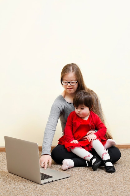 ノートパソコンを見ながら子供を保持しているダウン症候群を持つ少女