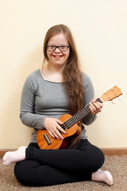 Девушка с синдромом Дауна держит гитару и улыбается