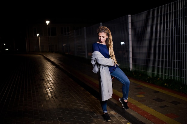Foto gratuita ragazza con i dreadlocks che cammina alla via di notte della città