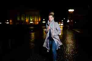 Foto gratuita ragazza con i dreadlocks che cammina alla via di notte della città