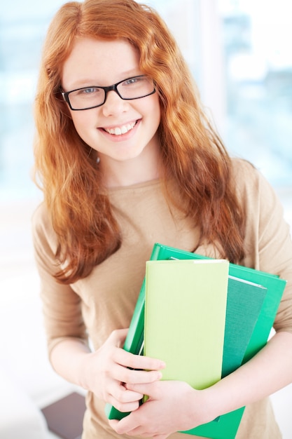 Ragazza con gli occhiali e libri di scuola