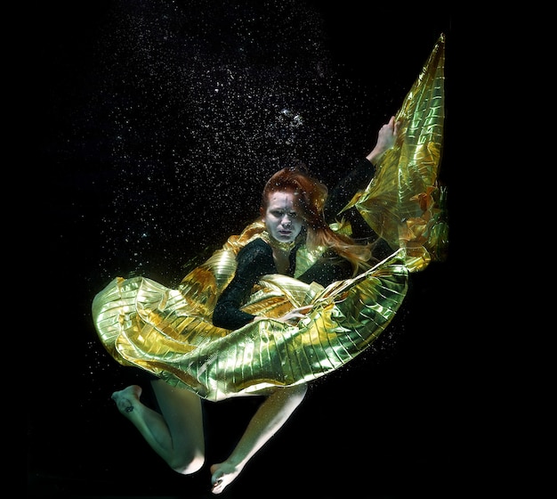 Foto gratuita ragazza con un mantello d'oro sotto l'acqua