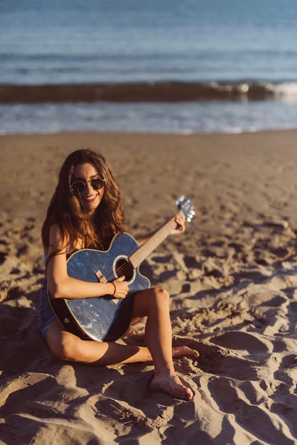 Girl with guitar playing at the beach
