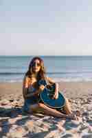 Free photo girl with guitar sitting on the sand