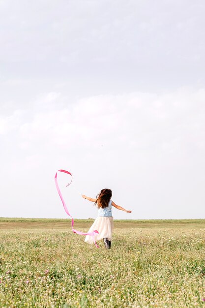 Girl with gymnastic ribbon running in field