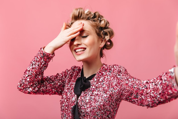 Girl with hair curlers makes selfie and covers her face with her hand