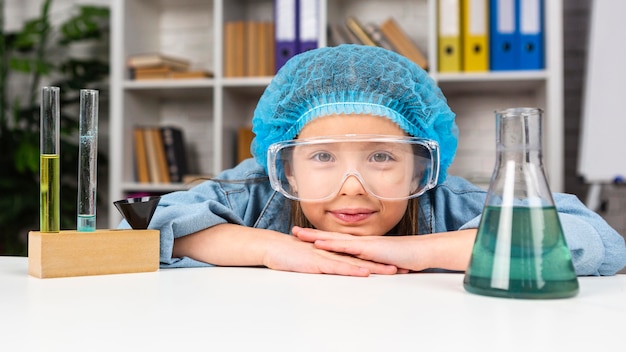 Girl with hair net and safety glasses doing science experiments with test tube