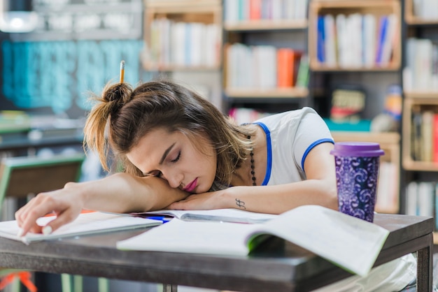 Ragazza con il hairbun che dorme sul tavolo