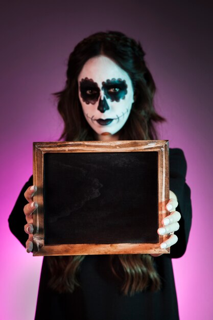 Girl with halloween makeup holding slate