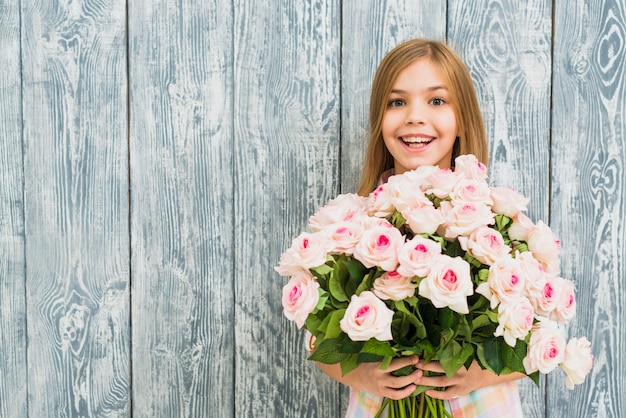 Foto gratuita ragazza con le rose della holding del viso sorpreso felice