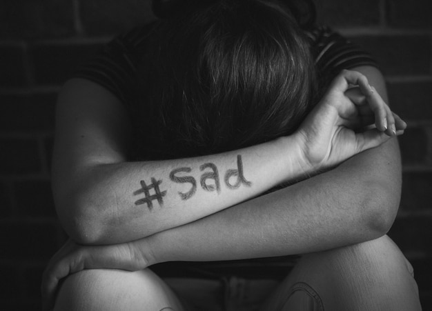 Девушка с грустным хэштегом, написанным на руке