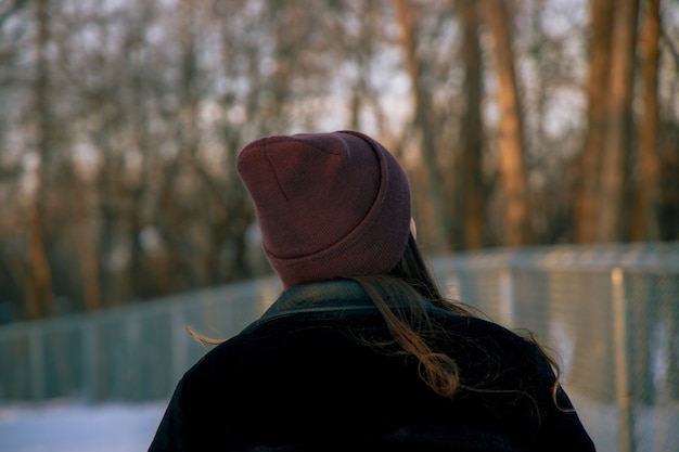 Foto gratuita ragazza con un cappello in piedi nella foresta durante il giorno