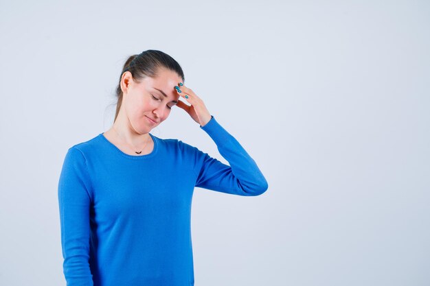 Girl with headache is holding hand on forehead on white background