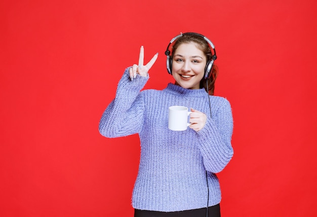 Girl with headphones enjoying the taste of coffee. 