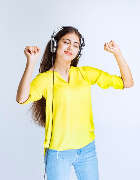 Girl with headphones listening the music and dancing with passion.