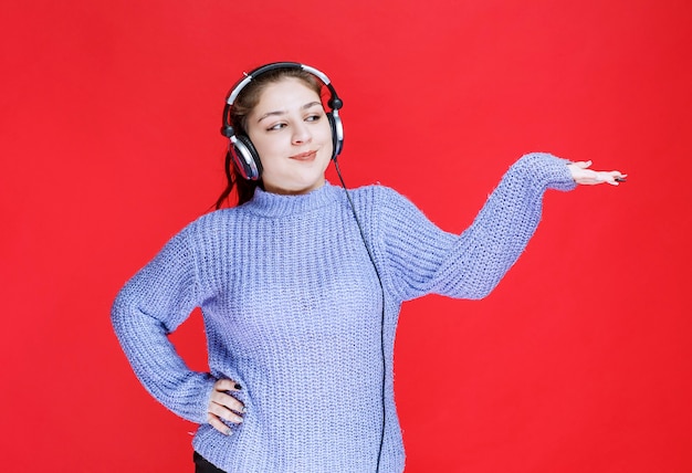 Girl with headphones pointing at something on the right.