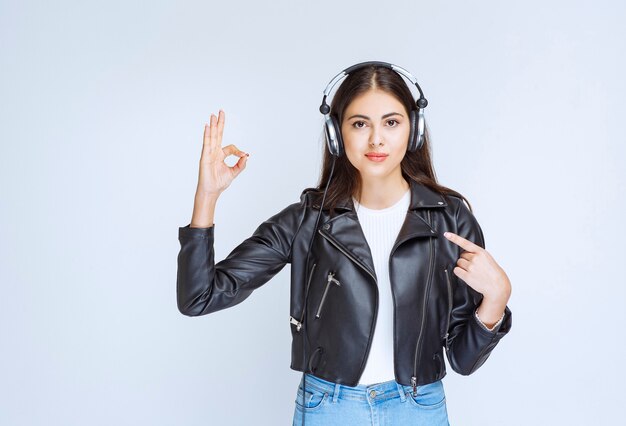 Girl with headphones showing enjoyment sign. 
