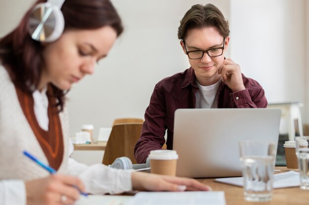 Girl with headphones using laptop along her classmates during group study