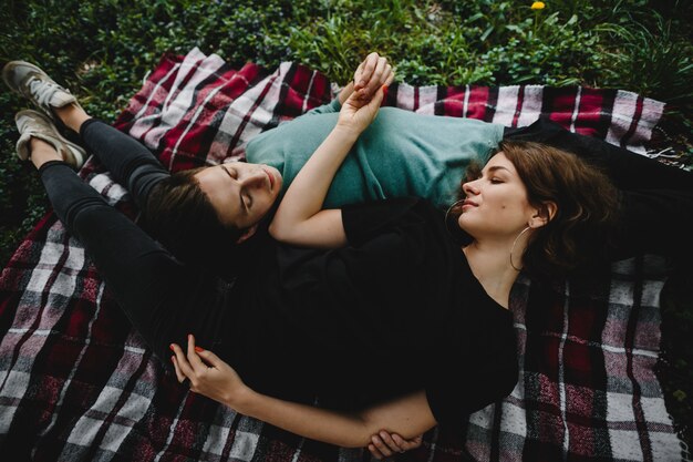 Girl with her boyfriend lie on a plaid and look at each other