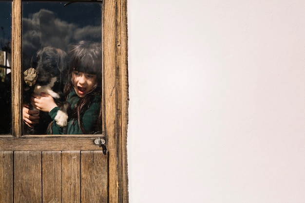 Free photo girl with her dog seen through transparent glass door