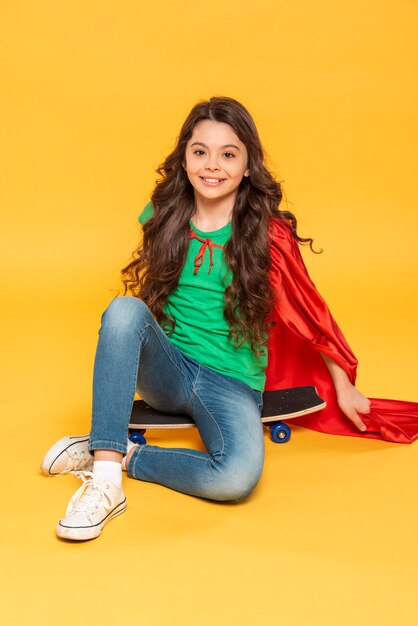 Girl with hero costume sitting on skateboard