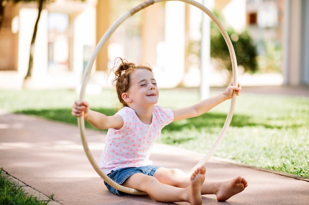 Girl with hula hoop sitting on path