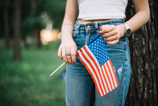 ジーンズと自然のアメリカの旗を持つ少女