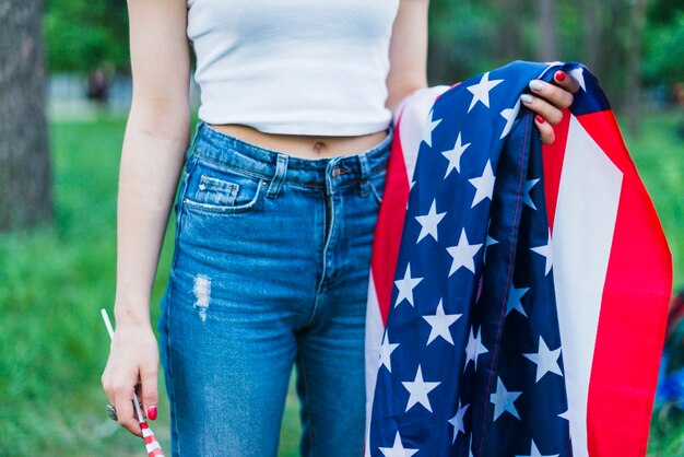 ジーンズと自然のアメリカの旗を持つ少女