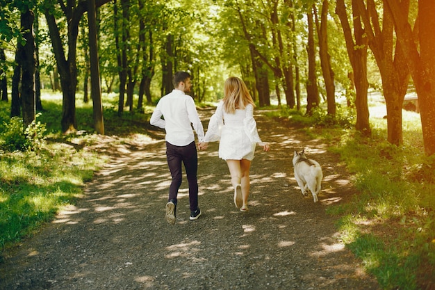  girl with light hair dressed in white dress is playing along with her dog and boyfriend