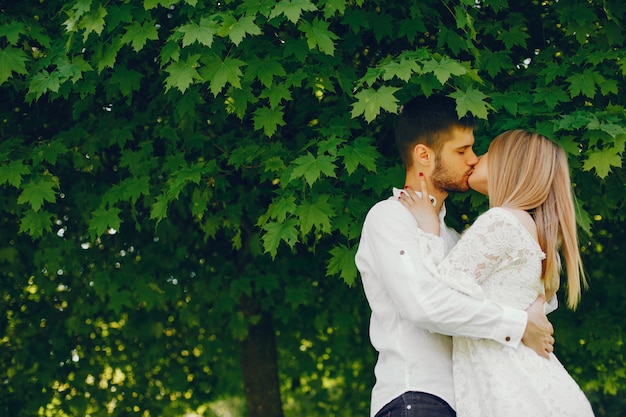 Foto gratuita ragazza con capelli chiari e un vestito bianco in una foresta assolato con il suo ragazzo