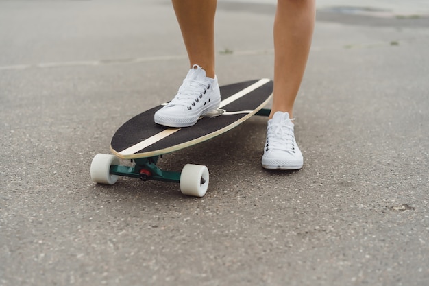 girl with long hair skates on a skateboard. street, active sports