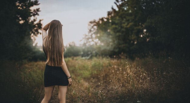 Girl with long hair surrounded by trees in a forest under the sunlight